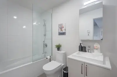 a white bathroom with a toilet and a shower at Cute Gem in Downtown Montreal in Montréal