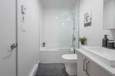 a white bathroom with a toilet and a shower at Cute Gem in Downtown Montreal in Montréal