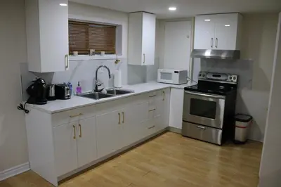 a kitchen with white cabinets and a sink and a stove at Perfect location brand new basement 1 bedroom full basement with kitchen in unit laundry separated in Laval