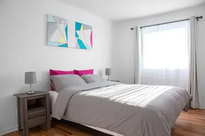 a white bedroom with a large bed and a window at Big Luxury 2 Bedroom Condo, Free Parking, Near Downtown, King size Bed in Longueuil