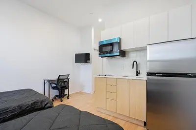 a small kitchen with a refrigerator and a sink at Magnificent Studio with FREE parking near downtown in Montréal