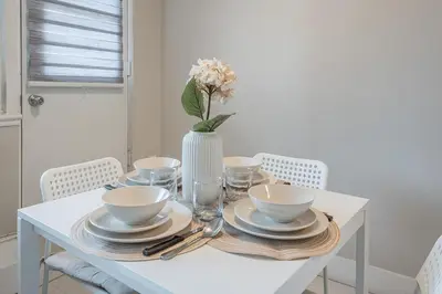 a white table with plates and a vase with flowers at Cozy 1BR - Heart of Montreal in Montréal