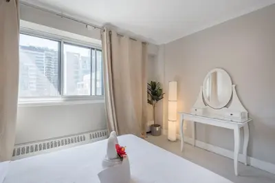 a white bedroom with a mirror and a bed at Cozy 1BR - Heart of Montreal in Montréal