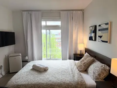 a bedroom with a white bed and a window at McGill Les Petits Studios, Downtown & Nightlife in Montréal