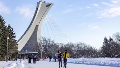 a group of people skiing in the snow in front of a bridge at McGill Les Petits Studios, Downtown & Nightlife in Montréal