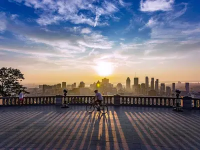 a man riding a bike on a bridge with a city skyline at McGill Les Petits Studios, Downtown & Nightlife in Montréal