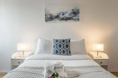 a bedroom with a white bed with two lamps at 1BR Downtown MTL - Walk to Old Port in Montréal