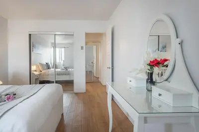 a white bedroom with a table and a mirror at 1BR Downtown MTL - Walk to Old Port in Montréal