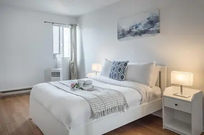 a white bedroom with a large white bed and a window at 1BR Downtown MTL - Walk to Old Port in Montréal