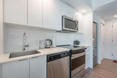 a white kitchen with a sink and a microwave at Downtown Montreal 1BR - Sleeps 4 in Montréal