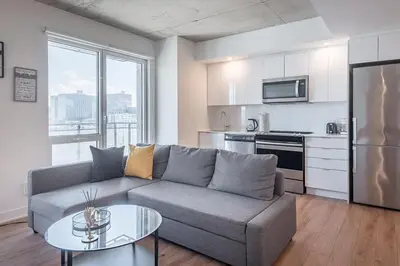 a living room with a couch and a table and a kitchen at Downtown Montreal 1BR - Sleeps 4 in Montréal