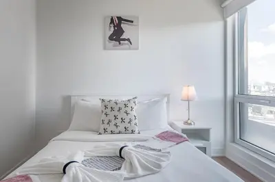 a white bed in a white room with a window at Downtown Montreal 1BR - Sleeps 4 in Montréal