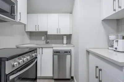 a kitchen with white cabinets and a stainless steel dishwasher at Modern 1BR - Central Location in Montréal