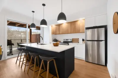 a kitchen with white cabinets and a large island with bar stools at Magnifique Condo pour 4 à Orford in Magog-Orford