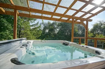 a hot tub under a wooden pergola at Bashtina Inn and Spa in Saint-Césaire