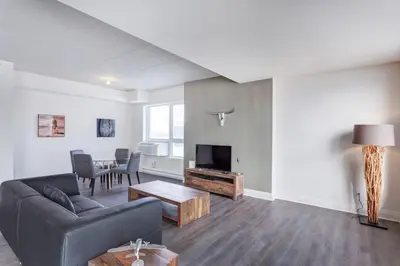 a living room with a couch and a tv and a table at Corporate Stays Equinoxe 2 Bedroom in Laval