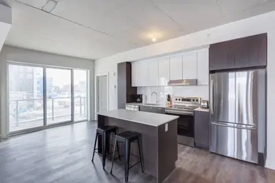 a kitchen with a refrigerator and a counter with stools at Corporate Stays Equinoxe 2 Bedroom in Laval