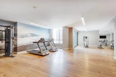 a gym with cardio equipment in a large room at Corporate Stays Equinoxe 2 Bedroom in Laval