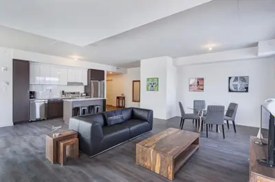 a living room with a black couch and a table at Corporate Stays Equinoxe 2 Bedroom in Laval