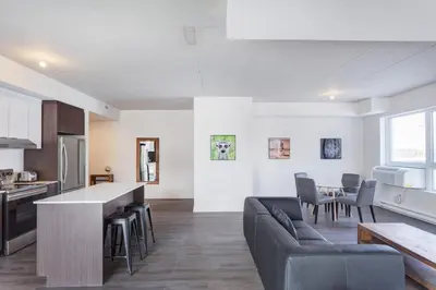 a kitchen and living room with a couch and a table at Corporate Stays Equinoxe 2 Bedroom in Laval