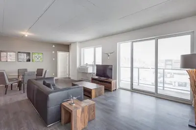 a living room with a couch and a television at Corporate Stays Equinoxe 3 Bedrooms in Laval
