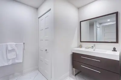a white bathroom with a sink and a mirror at Corporate Stays Equinoxe 3 Bedrooms in Laval