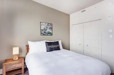 a bedroom with a large white bed and a cabinet at Corporate Stays Equinoxe 3 Bedrooms in Laval