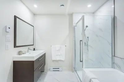 a white bathroom with a sink and a shower at Corporate Stays Equinoxe 3 Bedrooms in Laval