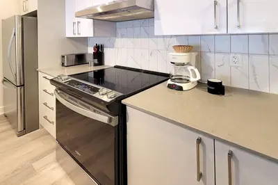 a kitchen with white cabinets and a blender on the counter at Corporate Stays Blum 1 Bedroom in Brossard
