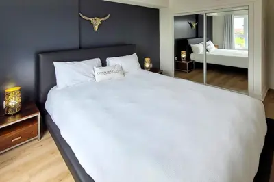 a large white bed in a bedroom with a mirror at Corporate Stays Blum 1 Bedroom in Brossard
