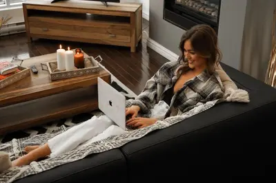 a woman sitting on a couch with a laptop at Corporate Stays Blum 1 Bedroom in Brossard