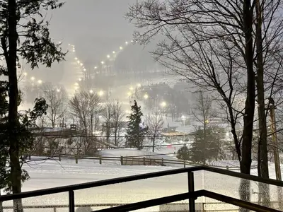 a snow covered park with a fence and a city at Ski in out condo sur la montagne in Bromont