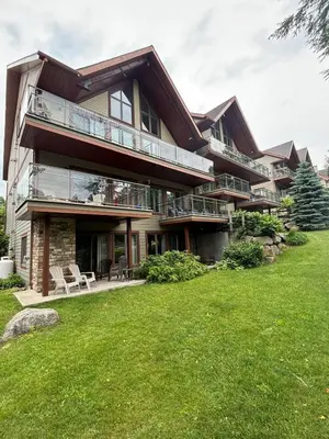 a large house with a green lawn in front of it at Ski in out condo sur la montagne in Bromont