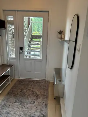 a hallway with a door with a mirror and a rug at Ski in out condo sur la montagne in Bromont