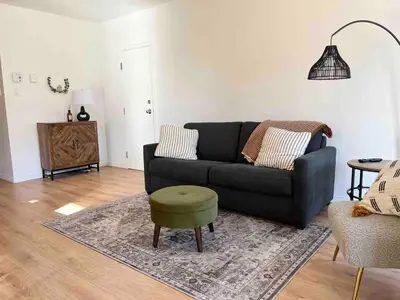a living room with a black couch and a green stool at Ski in out au pied des pentes in Bromont