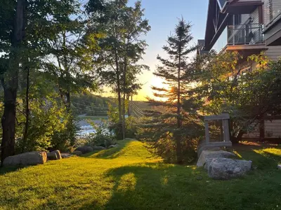 a yard with rocks and trees and a house at Ski in out au pied des pentes in Bromont