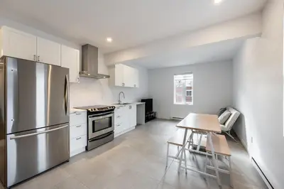 a kitchen with white cabinets and a stainless steel refrigerator at Séjour Coup de Cœur! Confort et emplacement idéal in Montréal