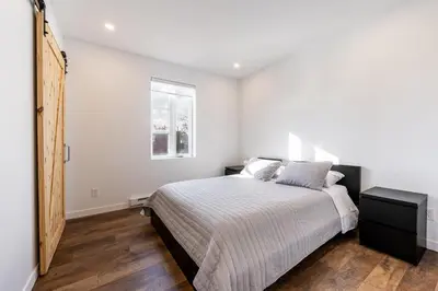 a white bedroom with a bed and a window at Séjour Coup de Cœur! Confort et emplacement idéal in Montréal