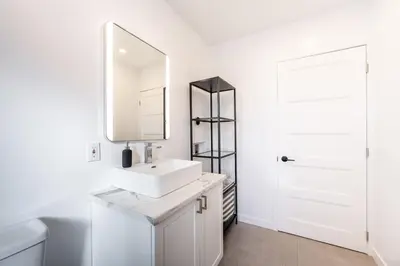 a white bathroom with a sink and a mirror at Séjour Coup de Cœur! Confort et emplacement idéal in Montréal
