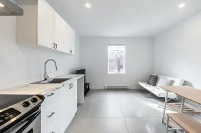 a kitchen with white cabinets and a table at Séjour Coup de Cœur! Confort et emplacement idéal in Montréal