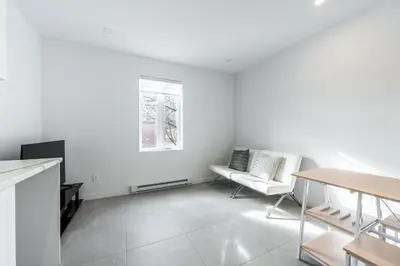 a white living room with a table and a couch at Séjour Coup de Cœur! Confort et emplacement idéal in Montréal