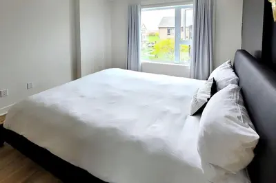 a white bed with pillows in a bedroom with a window at Corporate Stays Blum 2 Bedrooms in Brossard