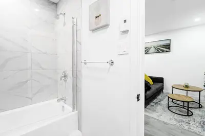 a white bathroom with a shower and a tub at Appartement 2 chambres Downtown Montréal in Montréal