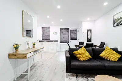 a living room with a black couch and a kitchen at Appartement 2 chambres Downtown Montréal in Montréal