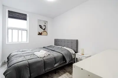 a white bedroom with a bed and a window at Appartement 2 chambres Downtown Montréal in Montréal