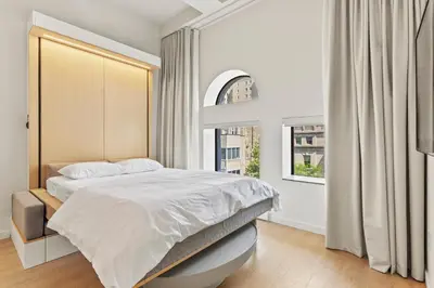 a white bedroom with a bed and a window at Miles by Alta in Montréal