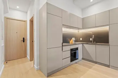 a kitchen with white cabinets and a wooden door at Miles by Alta in Montréal