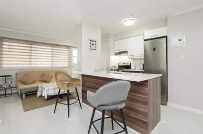 a kitchen and living room with a counter and chairs at Séjour idéal au cœur de Montréal in Montréal