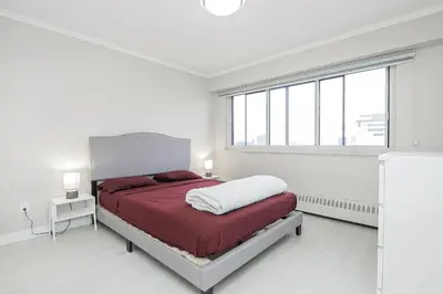 a white bedroom with a bed and a large window at Séjour idéal au cœur de Montréal in Montréal