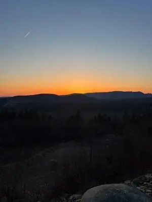 a sunset in the mountains with a rock in the foreground at Chalet Le Mona in Notre-Dame-Des-Bois
